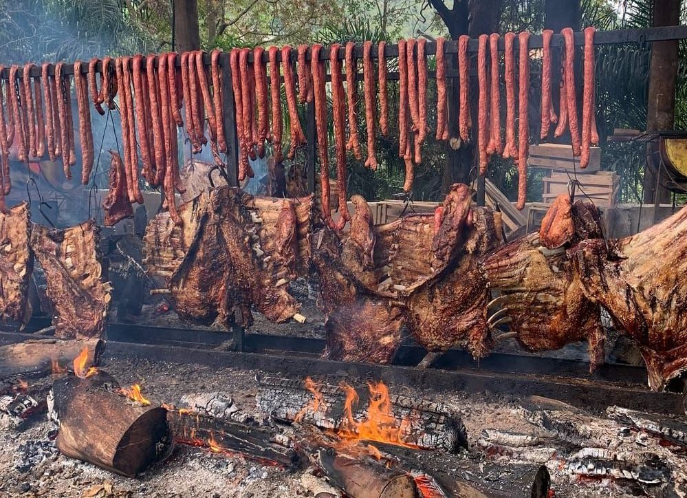 Espetos com carnes variadas ao redor do fogo de chão