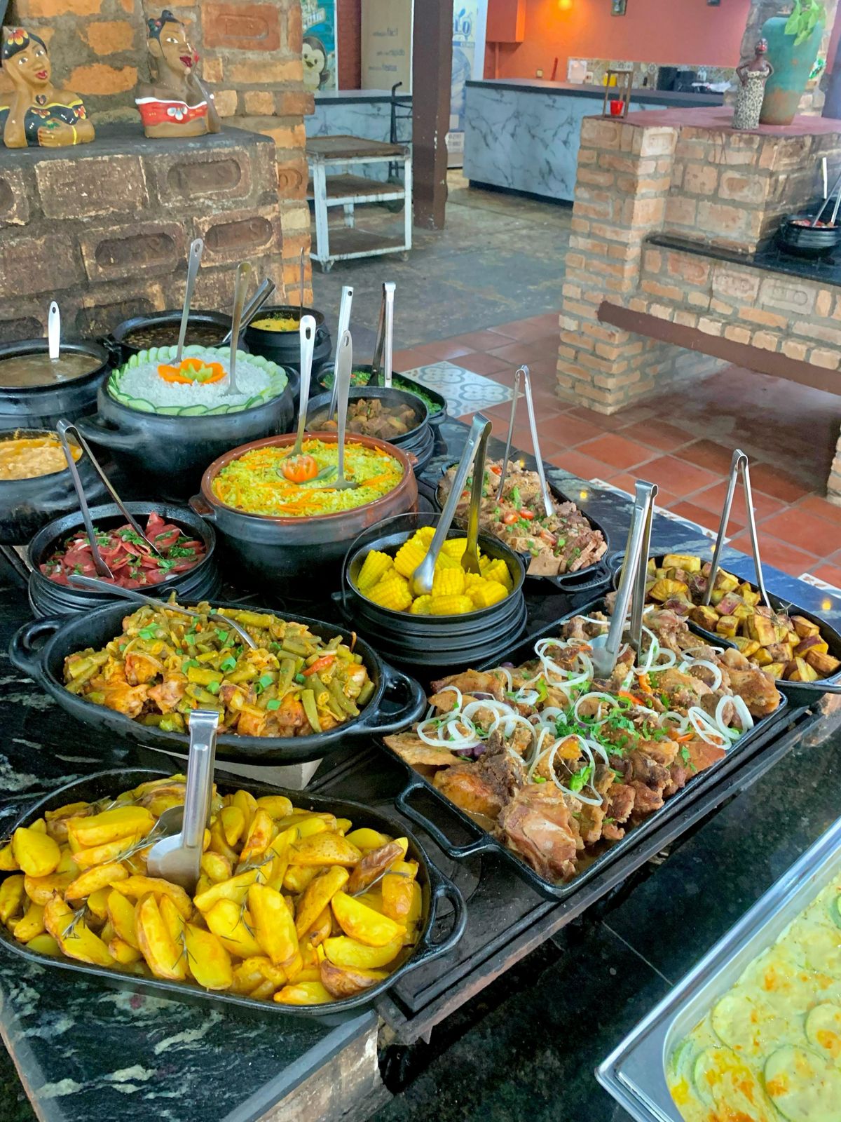 Mesa de buffet com panelas de barro e guarnições